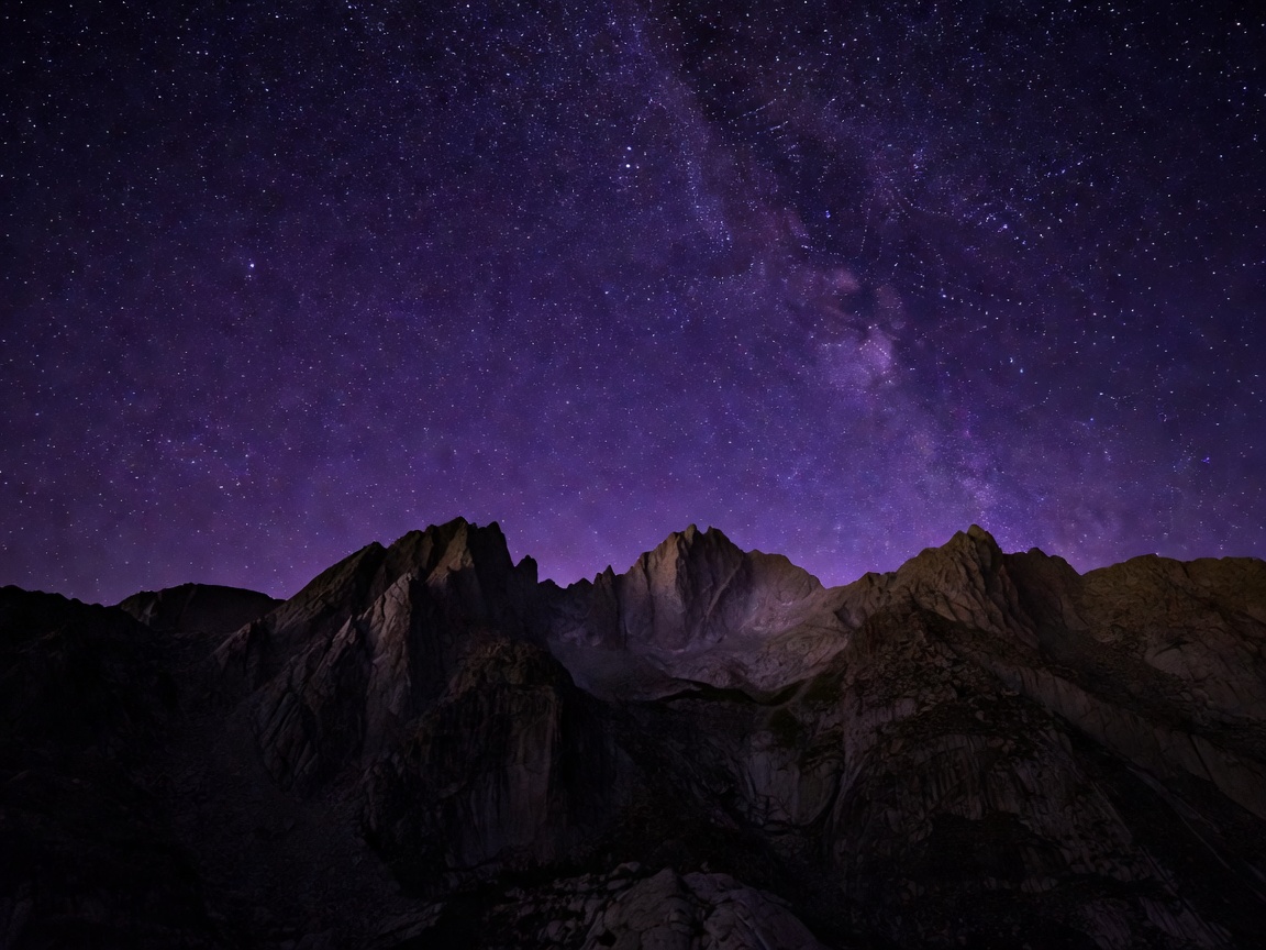 Deep purple starry night sky over mountain peaks
